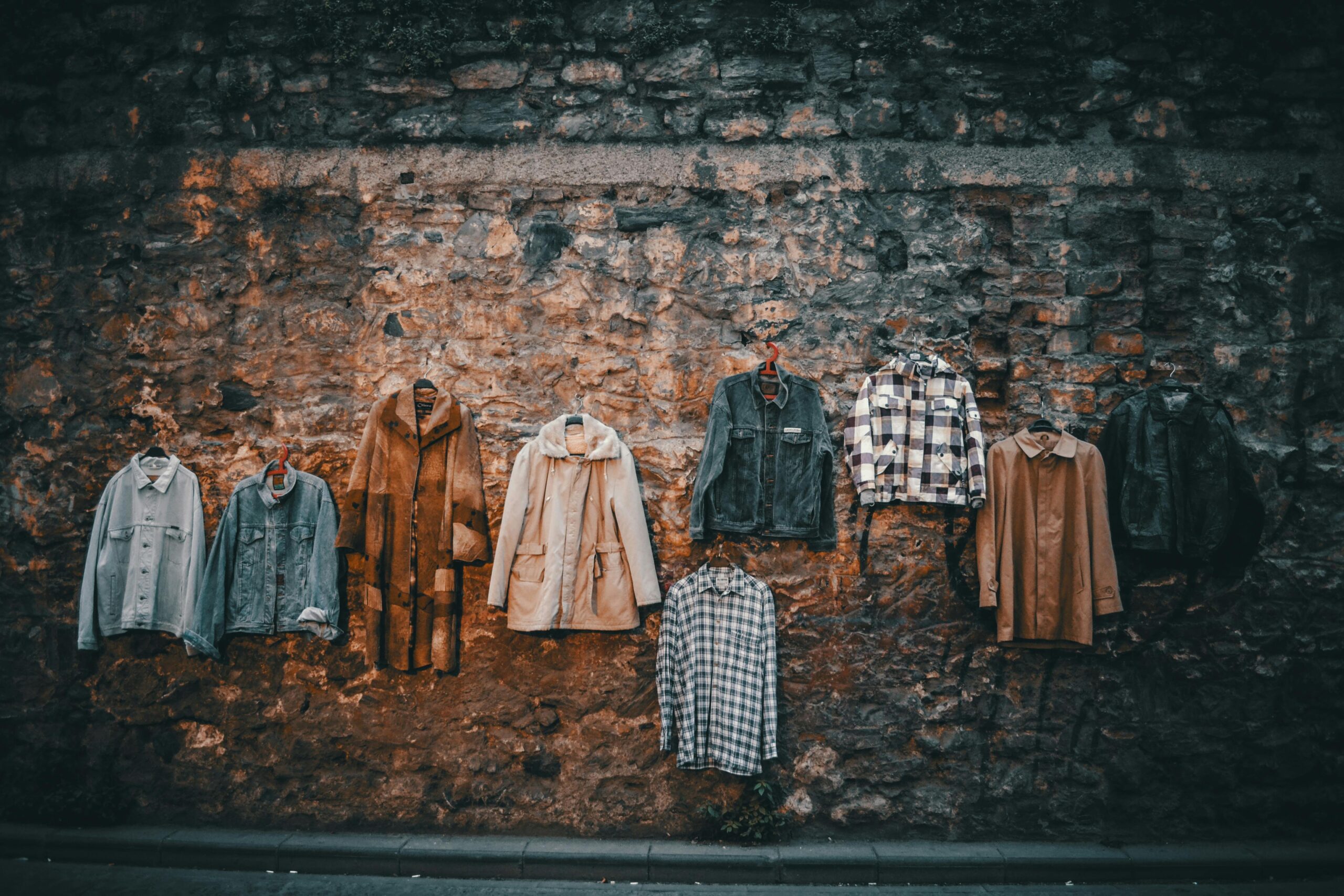 POPClothe Different shirts and jackets placed for sale on aged stone wall of urban street